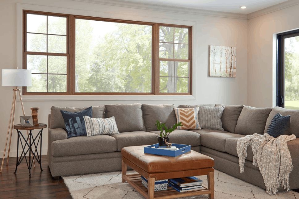Living room with wood-look replacement windows overlooking a tree line.